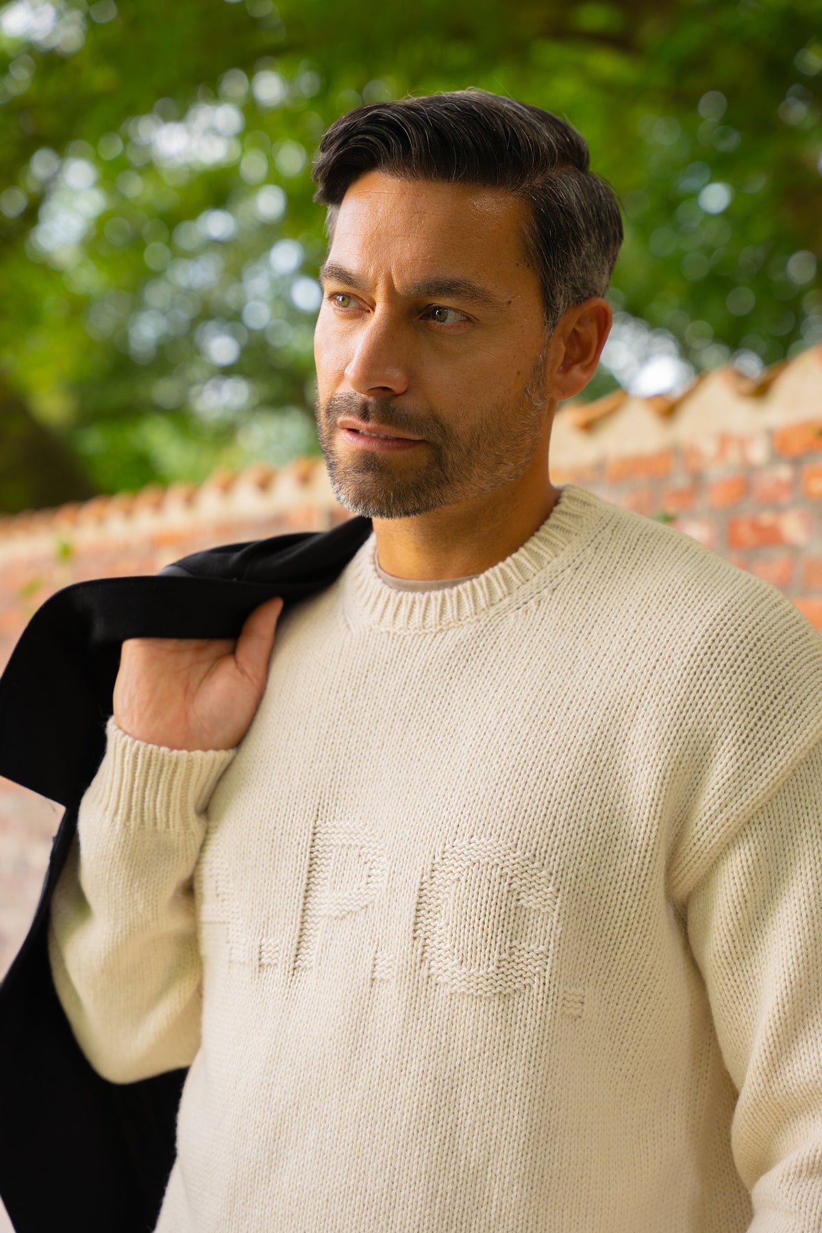 Look HW26/27 – Crème A.P.C. trui met zwarte jas over de schouder | Gentlemen Mode