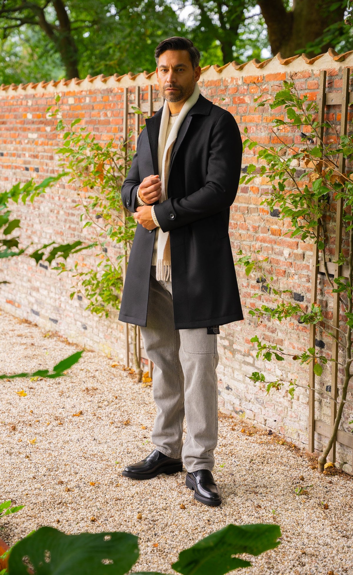 Look HW26/27 – Zwarte wollen overjas met crème sjaal en grijze pantalon | Gentlemen Mode
